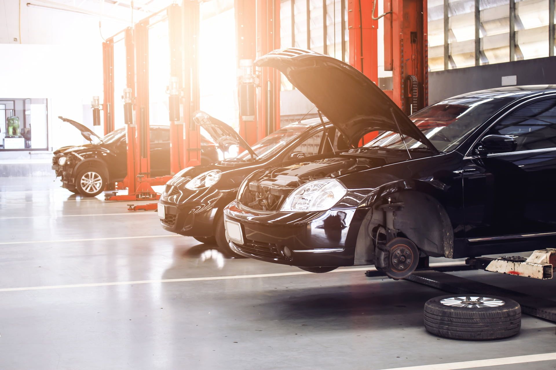 Ein Auto wird in einer Werkstatt repariert, während Mechaniker an verschiedenen Teilen arbeiten.